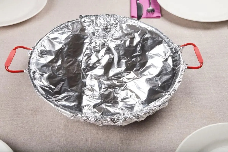 Some benefits of using aluminum foil in a slow cooker are that it can help distribute heat more evenly, prevent food from sticking, and make cleanup easier.